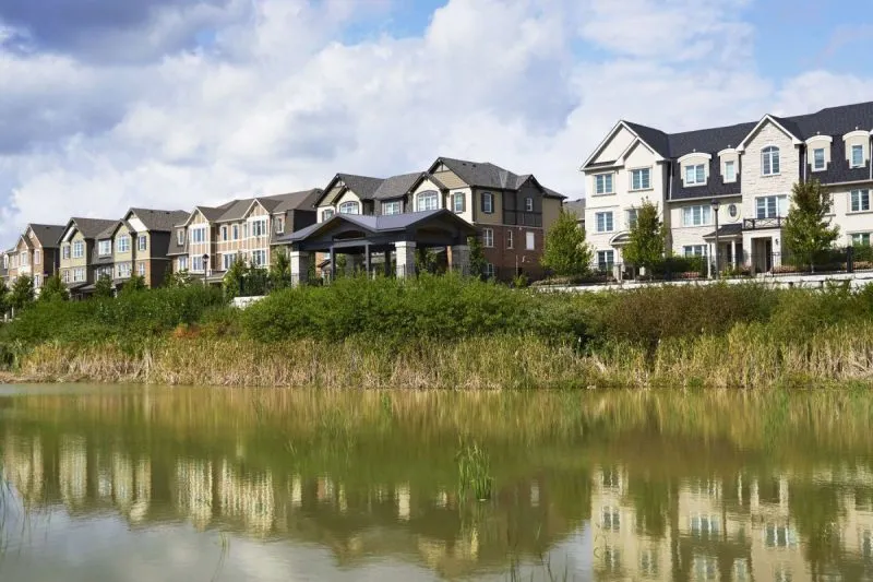 Townhomes and detached homes overlooking a pond at Upper Joshua Creek in Oakville
